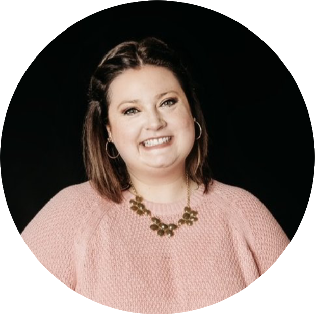 A woman in pink shirt and necklace smiling.