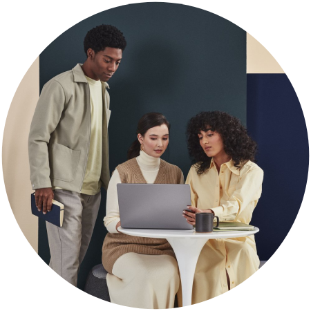 A group of people standing around a table with a laptop.