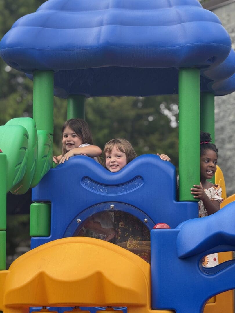 Three girls playing on a colorful playground.