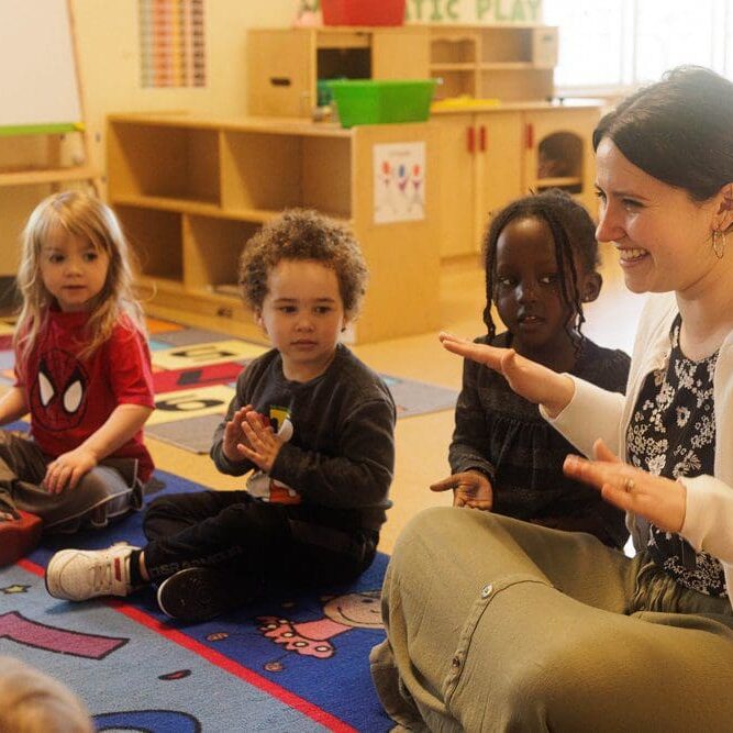 A woman sitting on the floor with children.